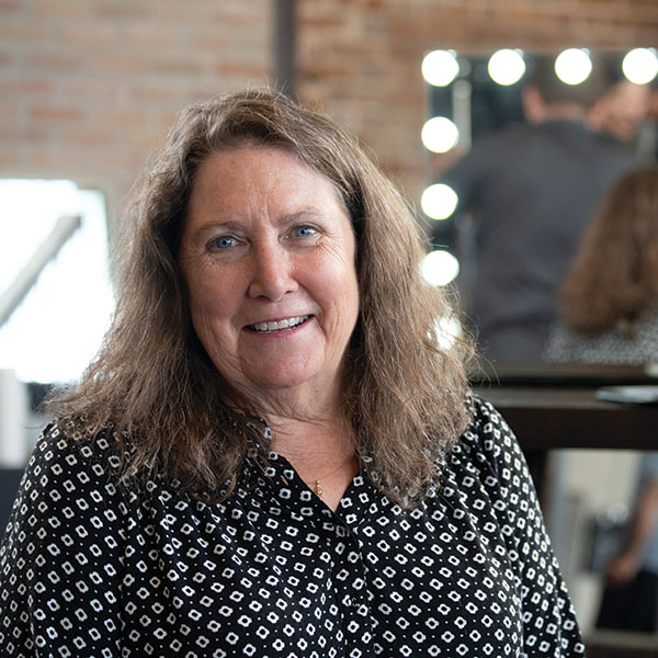 A woman smiling in front of a mirror in a salon. A woman smiling in front of a mirror in a salon.