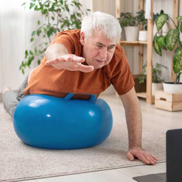 An older man doing exercises on a blue exercise ball. An Older Man Doing Exercises On A Blue Exercise Ball.