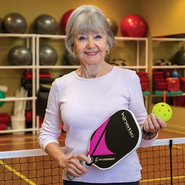 An older woman holding a tennis racket and ball. An older woman holding a tennis racket and ball.
